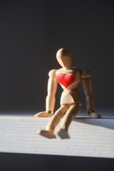 Wooden man figure with red heart on his breast. Valentines day background, creative texture and love concept