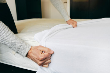 man covering a mattress with a mattress protector