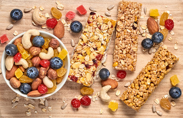 Cereal healthy snack. Granola bar with nuts and dry fruit berries. Diet food. Protein muesli bars isolated on wood background. Sport oatmeal bar, top view, closeup