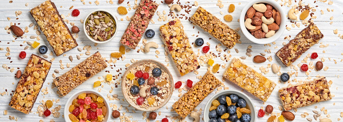 Cereal healthy snack. Granola bar with nuts and dry fruit berries. Diet food. Protein muesli bars isolated on wood background. Sport oatmeal bar, top view, closeup, banner - 339183003