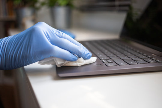 office sanitizing wipe wiping laptop keyboard with disinfecting wipes. Coronavirus COVID-19 sanitize cleaning disinfection of work desk.