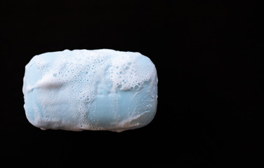 bar of soap with foam bubbles on black background. Top view.