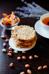 Oatmeal cookies and tea. A stack of oatmeal cookies on the table, next to a cup of tea, peanuts, dried apples and sprigs of lavender