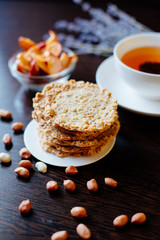 Oatmeal cookies and tea. A stack of oatmeal cookies on the table, next to a cup of tea, peanuts, dried apples and sprigs of lavender
