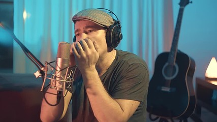 Musician in headphones playing on harmonica at home sitting on floor at evening time. Music hobby, Create own songs, learning online. 4K video
