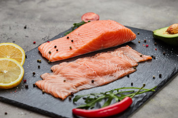 Fresh sliced salmon fillet with arugula, avocado and lemon on slate plate. Wild atlantic fish
