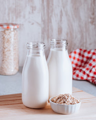 Non dairy oat milk in glass jars with reusable metal straws. Healthy vegan milk alternative still life, copy space. Substitute for traditional cow milk with oat flakes, healthy lifestyle concept