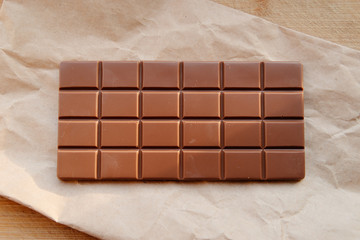A bar of milk chocolate. Homemade milk chocolate with almonds and dried strawberries. Pieces of milk chocolate. Unlabeled milk chocolate bar