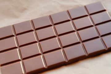 A bar of milk chocolate. Homemade milk chocolate with almonds and dried strawberries. Pieces of milk chocolate. Unlabeled milk chocolate bar