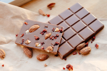A bar of milk chocolate. Homemade milk chocolate with almonds and dried strawberries. Pieces of milk chocolate. Unlabeled milk chocolate bar