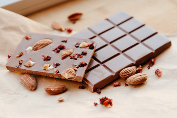 A bar of milk chocolate. Homemade milk chocolate with almonds and dried strawberries. Pieces of milk chocolate. Unlabeled milk chocolate bar