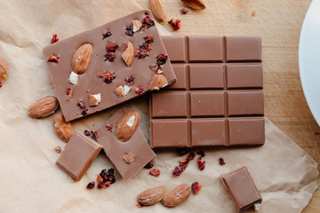 A bar of milk chocolate. Homemade milk chocolate with almonds and dried strawberries. Pieces of milk chocolate. Unlabeled milk chocolate bar