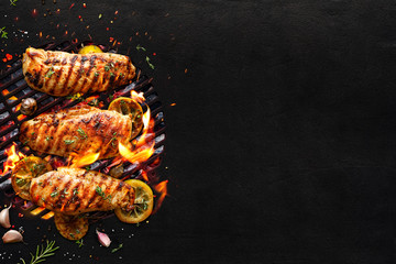 Grilled chicken breasts on a grill plate on black background with copy space, top view. Bbq background - obrazy, fototapety, plakaty