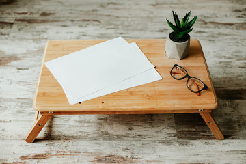wooden table with blank white paper and pen and glasses and notebook and plant. workplace. business. 