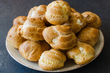 Homemade profitroles pastry filled with custard. Eclairs with cream, french dessert.