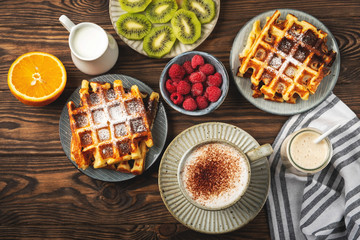 Belgian waffles, coffee, yogurt, fruits and berries on a wooden background, breakfast concept.