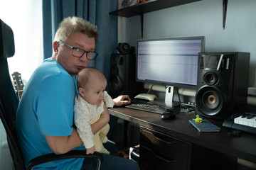 Dad sits at a computer with a baby