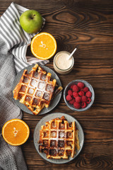Belgian waffles, yogurt, fruits and berries on a wooden background, breakfast concept.