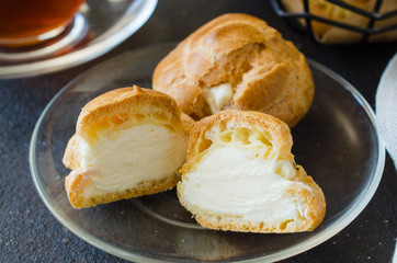 Homemade profitroles pastry filled with custard. Eclairs with cream, french dessert.