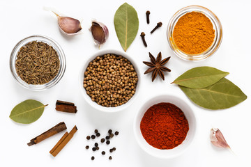 set of assorty colorful spices and herbs in bowls on white background, flat lay, top view