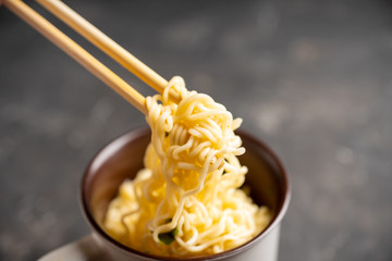 Instant noodles in cup on the rustic background. Selective focus. Shallow depth of field.
