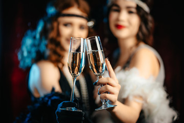 Beautiful flappers women dressed in style of Roaring twenties drinking champagne. Vintage, retro party, fashion, girls friends concept