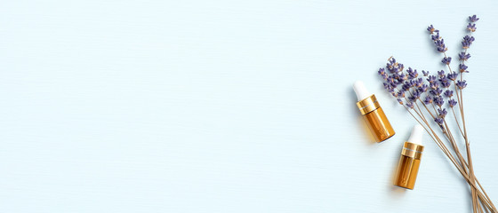 Lavender essential oil and dried flowers of lavender on blue background with copy space. Natural organic SPA cosmetic product. Flat lay, top view