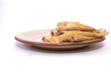 Fried smelt, fish lies in a clay plate. Simple wholesome food and place to copy. Isolated item.