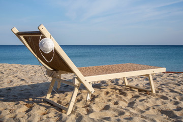 Protective mask on the beach chair. Desert beach due to Coronavirus (Covid19) quarantine. Campo...