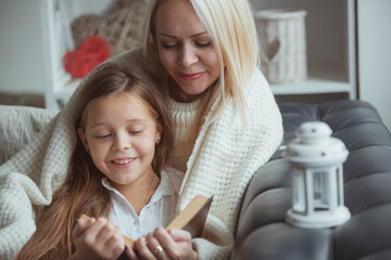 Mom and daughter read a book at home.