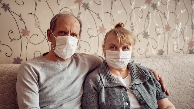 elderly couple in love in medical masks at home in quarantine, family values