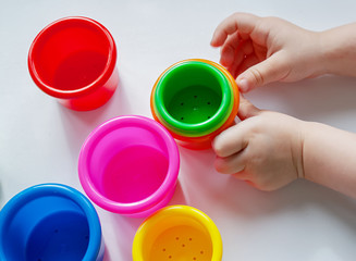 Colorful red, green, yellow, blue, pink and yellow plastic cups and baby pens