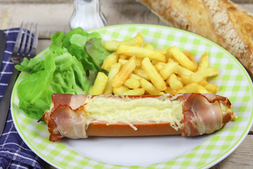 cervelas au fromage et bacon et frites dans une assiette