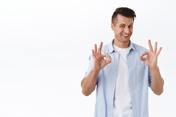 Count on me, guarantee best quality. Portrait of assuring good-looking man show okay signs as encourage to use this company service, recommend excellent product, standing pleased white background