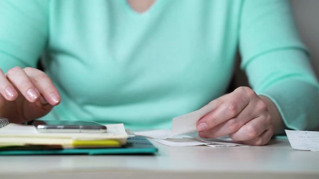 Female hands checking bills and writing down expenses