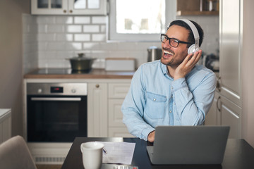 Man listening music on headset while using laptop.