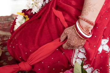 Fototapeta na wymiar bride in a red Sari. Beautiful traditional Indian wedding ceremony. bride's hand is decorated with mehendi and bracelets. Hindu wedding. indian engagement. Hindu the Vedic Yagya ceremony. vivah Yajna.