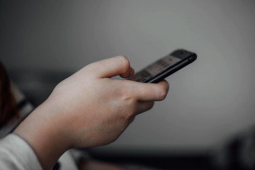 Young girl holds phone in hand sitting in room