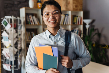 Image of happy asian man smiling and holding exercise books