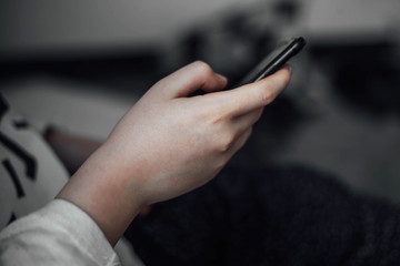 Young girl holds phone in hand sitting in room