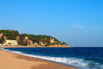 Fototapeta na wymiar Waves on the beach of Lloret de Mar in the summer. Catalonia, Spain.