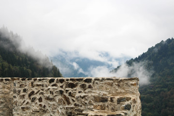 Stone wall and foggy mountains.