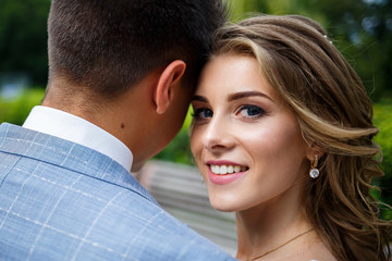 Young stylish guy in a suit the groom and the bride beautiful girl in a white dress with a train walk in the park on their wedding day