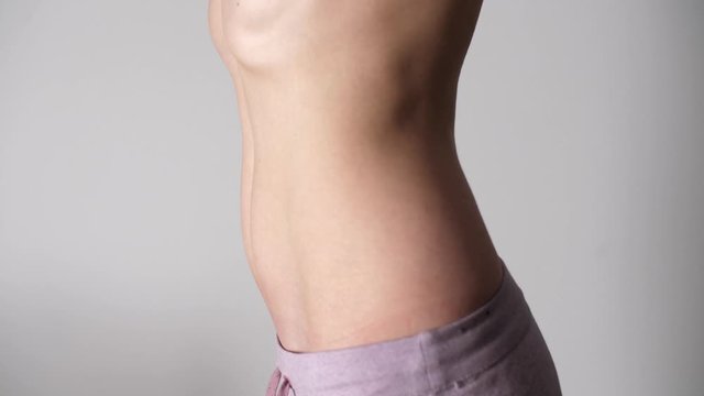 Woman pulls her stomach.Weight loss or weight gain during Quarantine. Attractive young woman with bare belly. Close-up of female belly of sexy girl. 