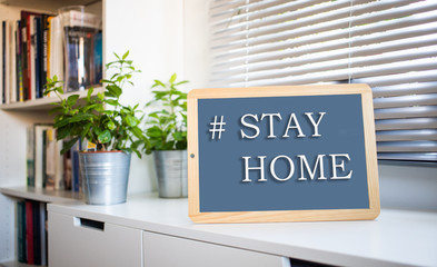 coronavirus quote stay home, save lives grey board sign with message of self isolation for social responsability on home  background. COVID-19 text to promote staying at home.