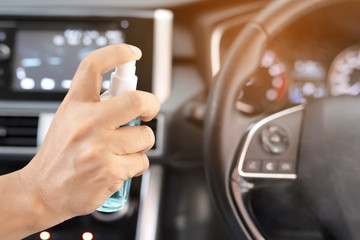 Cleansing car interior and spraying alcohol. Hand of man inject disinfectant liquid spray on steering wheel, contamination of germs or bacteria, prevent infection of Covid-19 virus