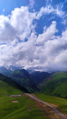 Mountain valley in clouds and green fields.