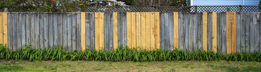 New fence planks replaced among old pieces.