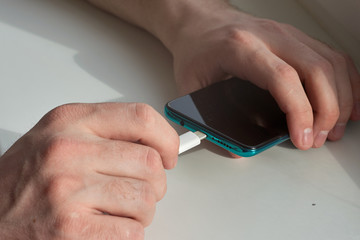 Man hands plugging a charger on a smart phone