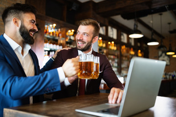 Happy young businessmen in suits are smiling and talking in a restaurant